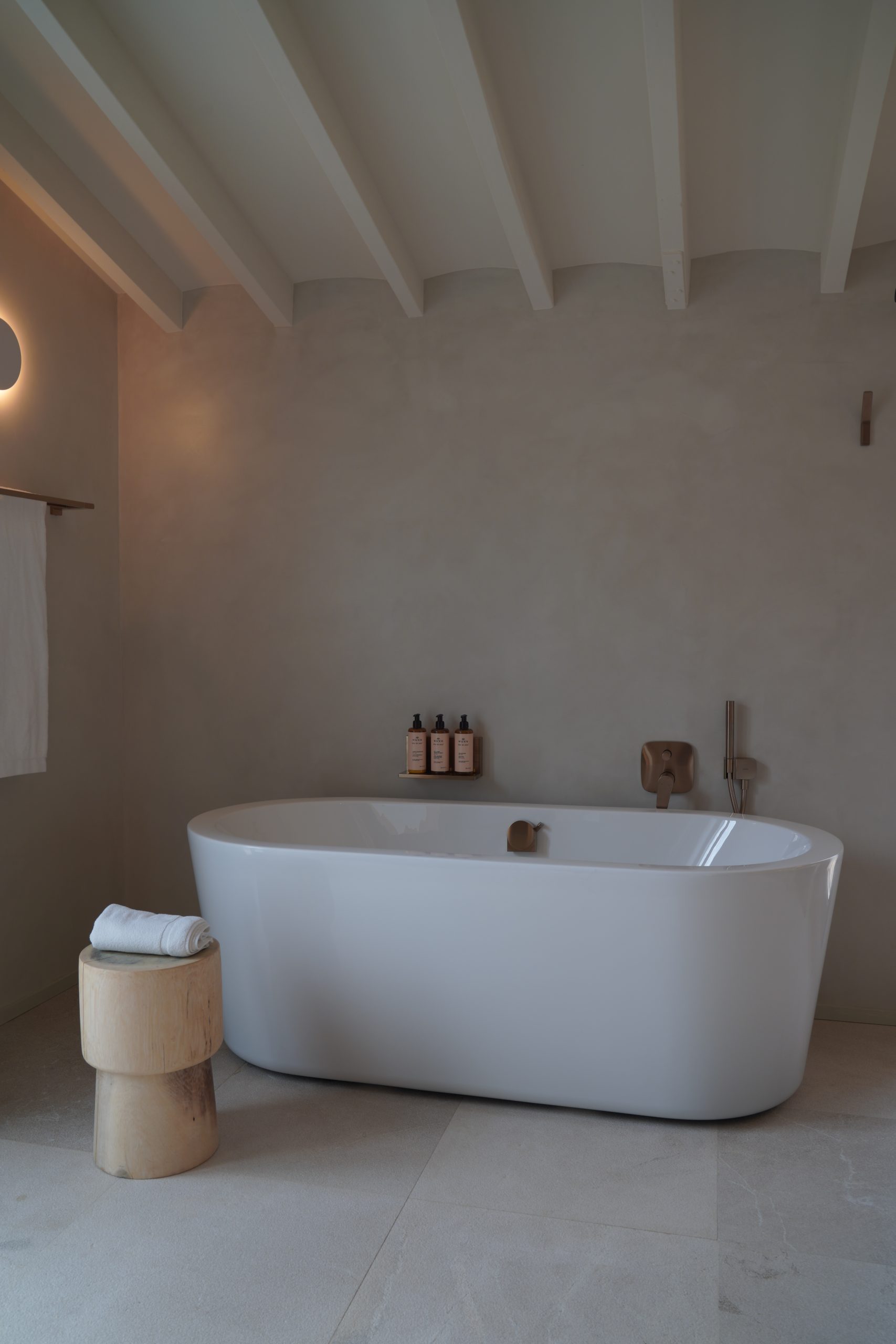 In deze luxe badkamer is de ultieme hammam sfeer gecreëerd bij het vrijstaand bad, met luxe handdoeken en mooie flesjes aan de wand.