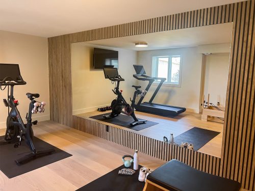 mooie fitnessruimte in huis grote spiegelwand houten latten wand