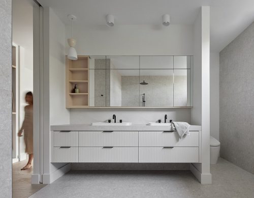 Voor deze luxe moderne badkamer heeft Studio Lau gekozen voor een grote strakke schuifdeur die in de muur verdwijnt. | Fotografie: Nanne Springer